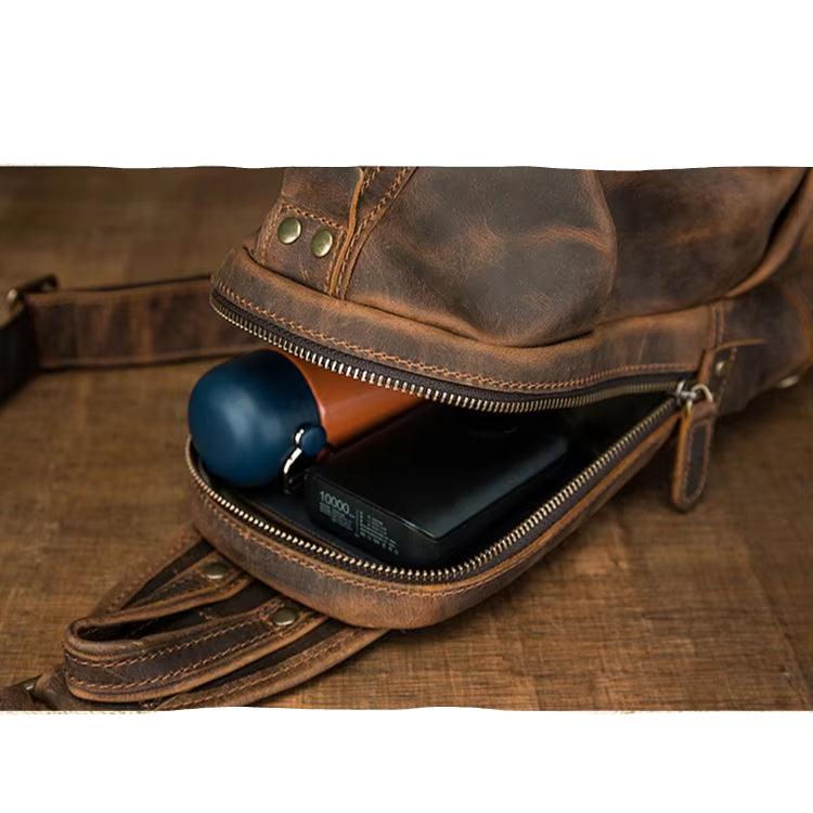 Zaino in pelle marrone con cerniera aperta, mostra power bank nero e oggetto blu all&