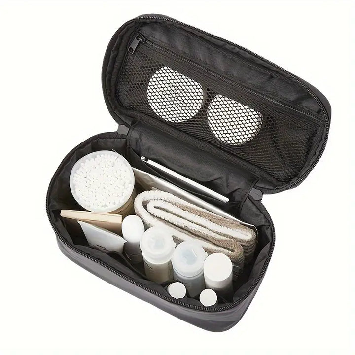 Borsa da toilette nera aperta con scomparti, contenente flaconi da viaggio, dischetti di cotone, asciugamano e accessori per la cura personale.