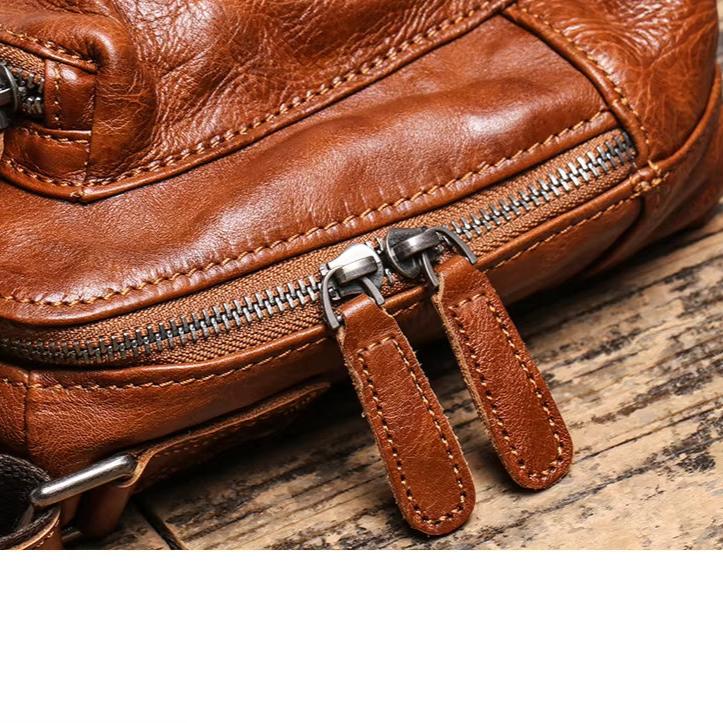 Borsa in pelle marrone con cerniera metallica su sfondo di legno. Accessorio moda elegante, ideale per uomo e donna.