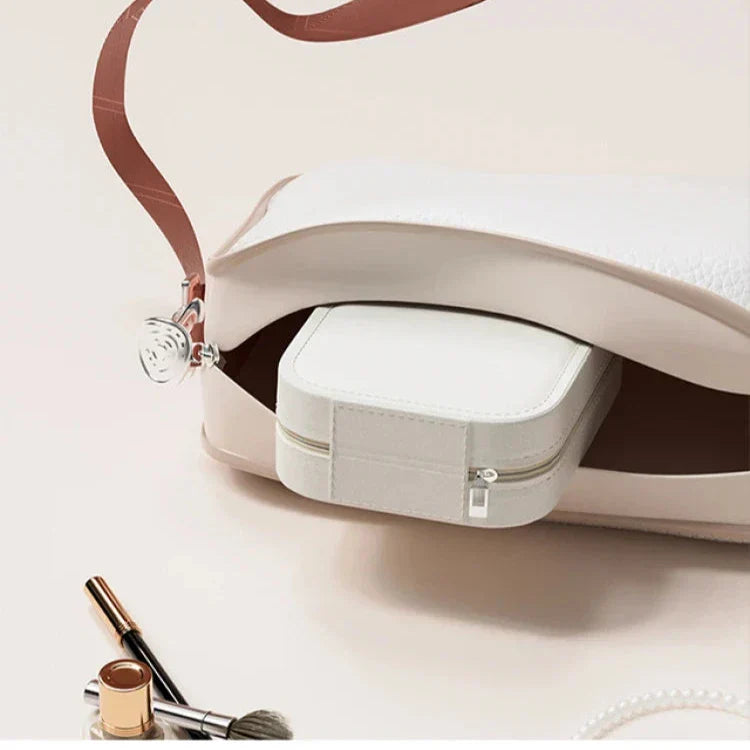 Borsa bianca in pelle aperta con pochette interna, accessori trucco e perle. Elegante e versatile, ideale per moda femminile e accessori di lusso.