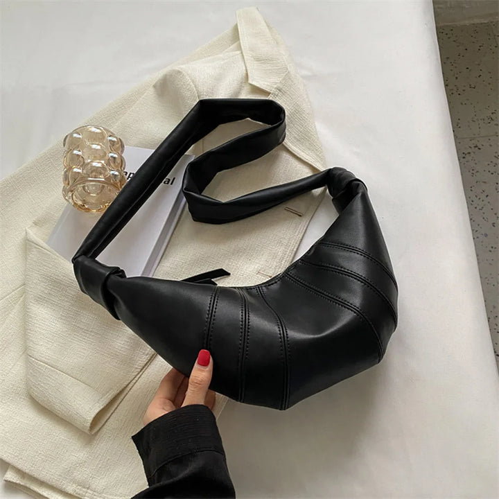 Borsa a tracolla nera in pelle su giacca beige, design moderno, accessorio moda donna, stile elegante, perfetta per look casual e formali.