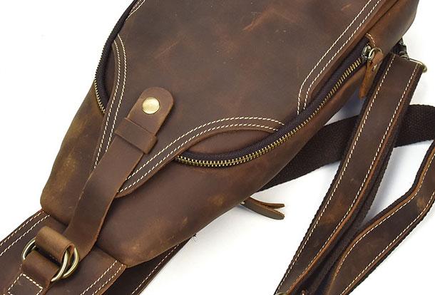 Zaino a tracolla in pelle marrone vintage, con cerniera e cuciture bianche, ideale per uomo e donna. Accessorio moda resistente e versatile.