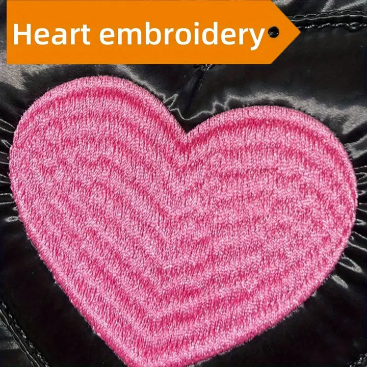 Ricamo a forma di cuore rosa su tessuto nero lucido, dettaglio moda, design elegante, accessorio abbigliamento, stile contemporaneo.