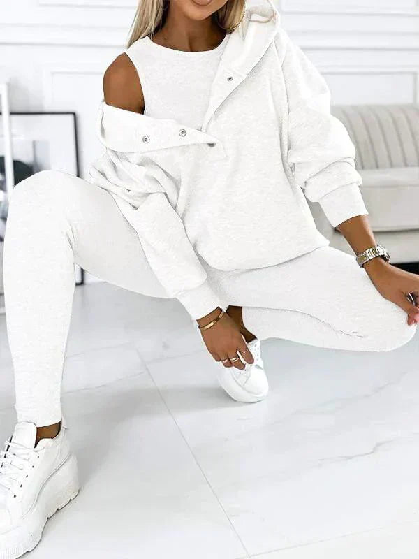 Donna in tuta bianca casual, felpa con cappuccio e pantaloni, posa moderna. Abbigliamento sportivo elegante, moda donna, comfort quotidiano.
