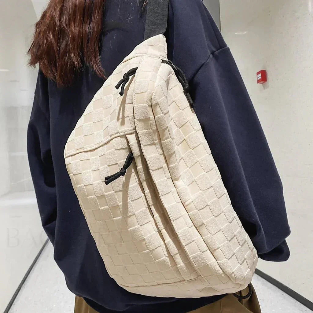 Zaino a tracolla beige intrecciato su persona con felpa nera. Design moderno, tessuto elegante, ideale per moda urbana e viaggi.