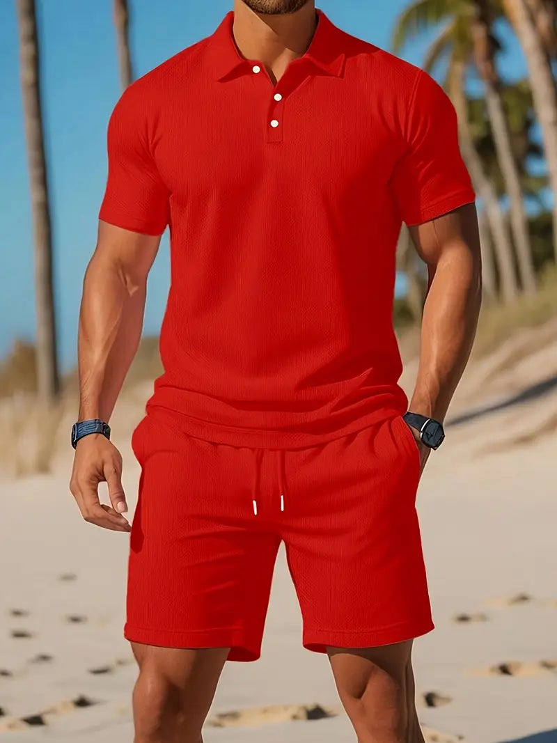 Uomo in completo estivo rosso su spiaggia, indossa polo e pantaloncini coordinati. Moda mare, abbigliamento casual estivo, stile vacanza.