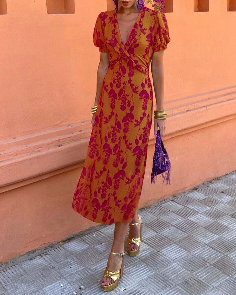 Abito midi arancione con stampa floreale fucsia, maniche a sbuffo, sandali dorati, borsa viola con frange. Moda estiva elegante e colorata.