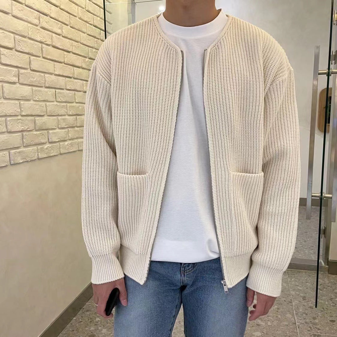 Uomo con cardigan beige a maglia, tasche frontali, indossa jeans blu e maglietta bianca. Moda casual, abbigliamento autunnale, stile urbano.