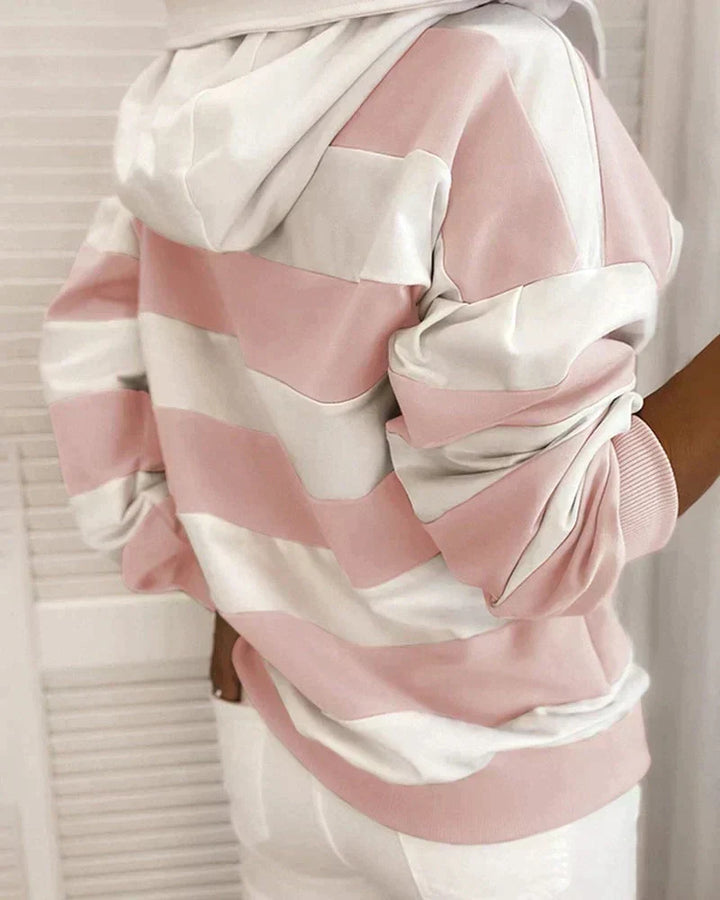Felpa a righe rosa e bianche con cappuccio, indossata da una persona di spalle. Design casual, moda autunnale, abbigliamento donna.
