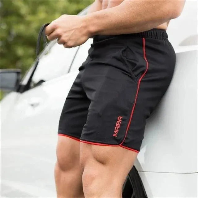 Pantaloncini sportivi neri da uomo con dettagli rossi, tasche laterali, indossati all'aperto. Ideali per fitness e allenamento estivo.