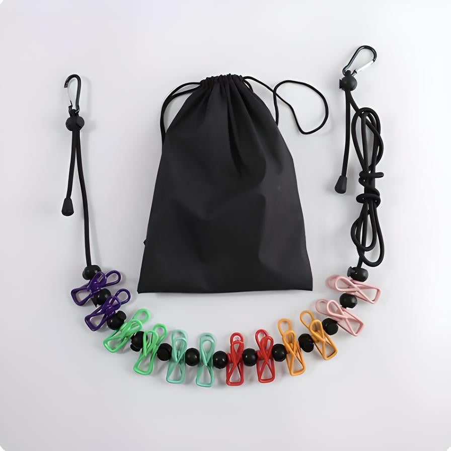 Sacca nera con corda elastica e mollette colorate per stendere i panni. Accessorio da viaggio compatto, ideale per campeggio e vacanze.
