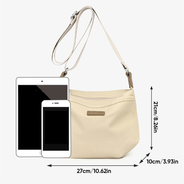 Borsa a tracolla beige in pelle sintetica con tasca frontale, dimensioni 27x10x21 cm, accanto a tablet e smartphone per confronto grandezza.