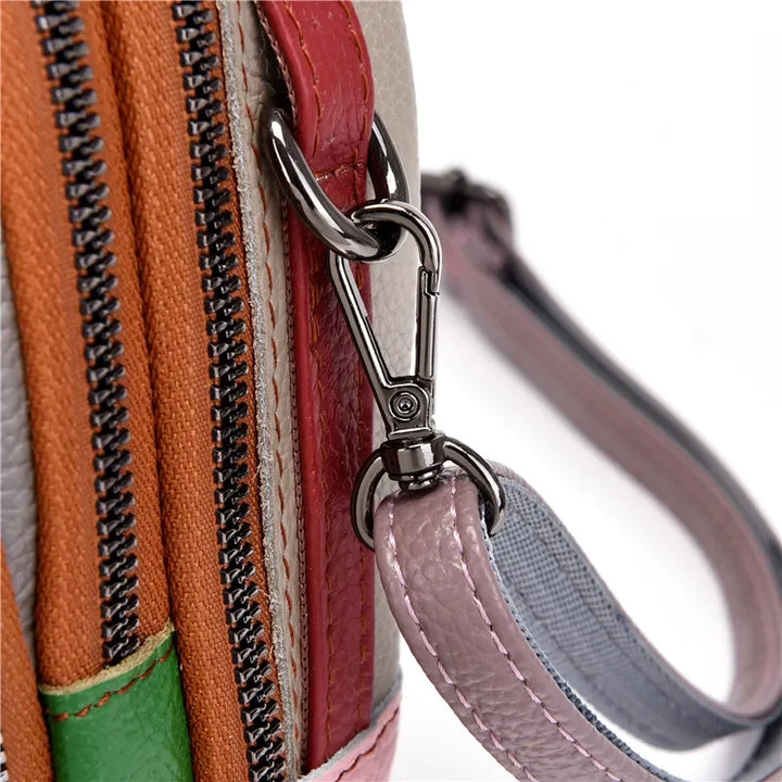 Primo piano di una borsa multicolore in pelle con cerniere e moschettone in metallo, design moderno e dettagli artigianali.