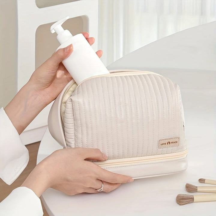 Borsa cosmetica beige con dispenser bianco, design trapuntato, chiusura a zip, ideale per organizzare prodotti di bellezza e accessori da viaggio.