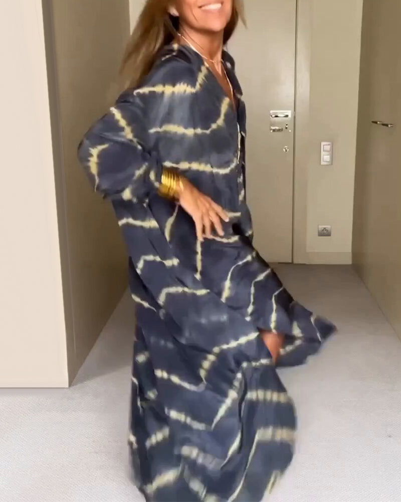 Donna che indossa un abito lungo tie-dye blu e giallo, sorridente e in movimento, in un ambiente interno moderno. Moda estiva, abbigliamento casual.