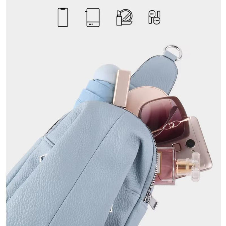 Zaino in pelle azzurra con occhiali da sole, smartphone, profumo e rossetto. Accessori moda donna, borsa elegante e funzionale.
