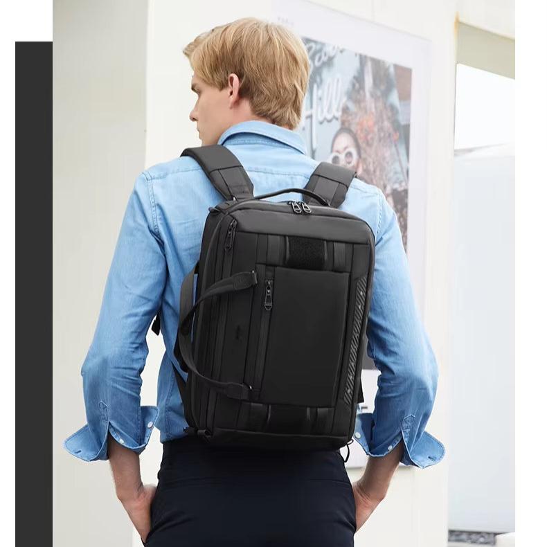 Uomo con zaino nero multifunzionale, design moderno, indossa camicia azzurra. Ideale per viaggi, lavoro, scuola. Elegante e pratico.