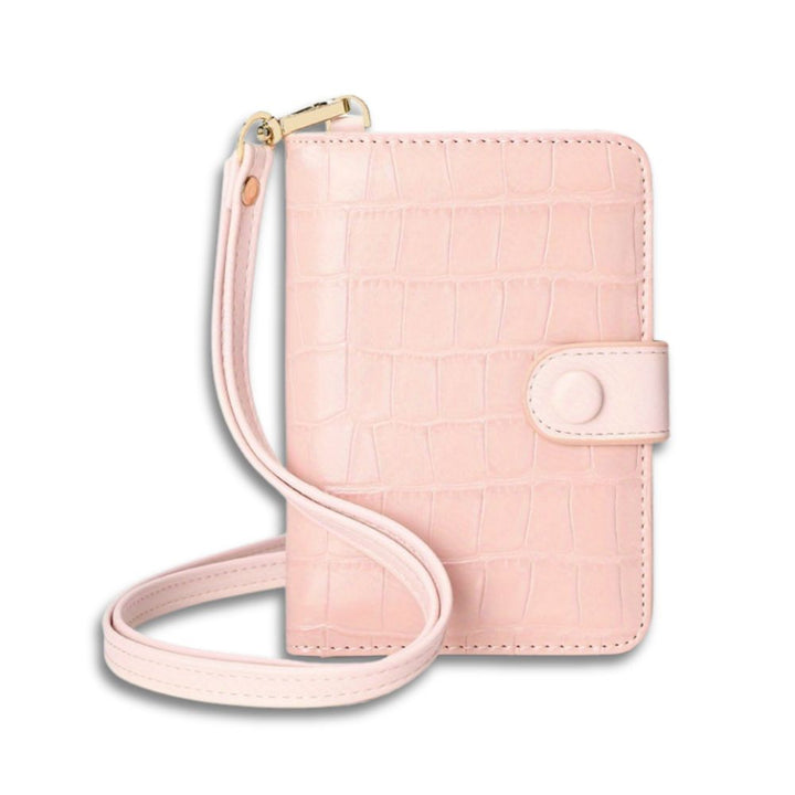 Portafoglio donna rosa in pelle con texture coccodrillo, chiusura a bottone, cinturino da polso. Elegante accessorio moda femminile.