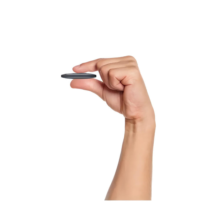 Mano che tiene un piccolo dispositivo rotondo nero, compatto e portatile. Ideale per tecnologia smart, accessori elettronici, gadget innovativi.