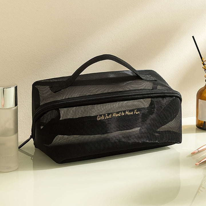 Borsa cosmetica nera in rete con cerniera, manico superiore e scritta dorata "Girls Just Want to Have Fun", su tavolo da toeletta.