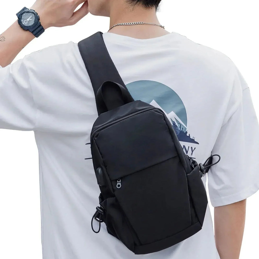 Zaino a tracolla nero unisex, indossato su maglietta bianca con stampa montagna. Design moderno, ideale per viaggi e uso quotidiano.