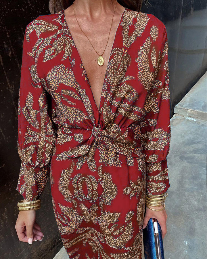 Abito rosso elegante con stampa floreale dorata, scollo a V profondo, maniche lunghe, accessori dorati, moda donna, stile sofisticato.