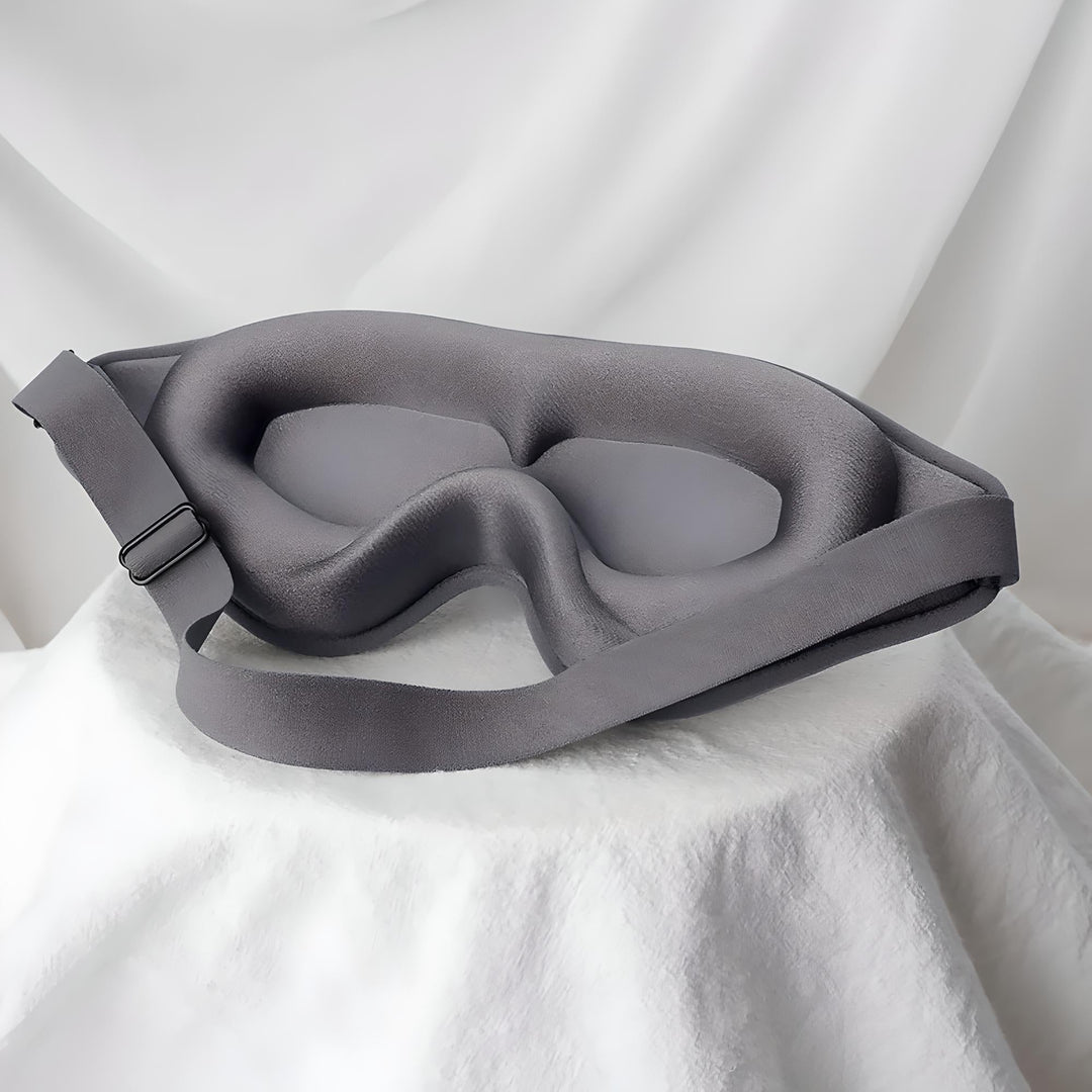 Maschera per dormire in memory foam grigia su sfondo bianco, design ergonomico, cinturino regolabile, ideale per sonno profondo e relax.