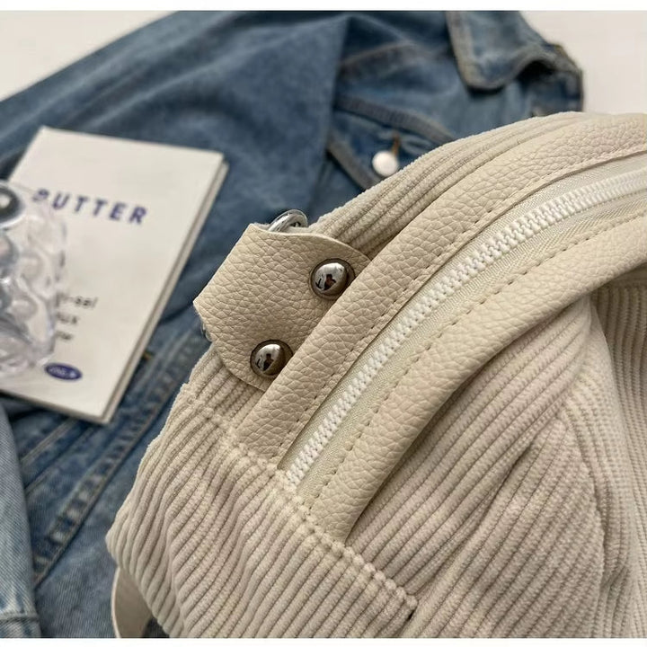 Zaino in pelle bianca su giacca di jeans, dettagli in metallo argentato, stile casual. Accessori moda, tendenze 2023, abbigliamento urbano.