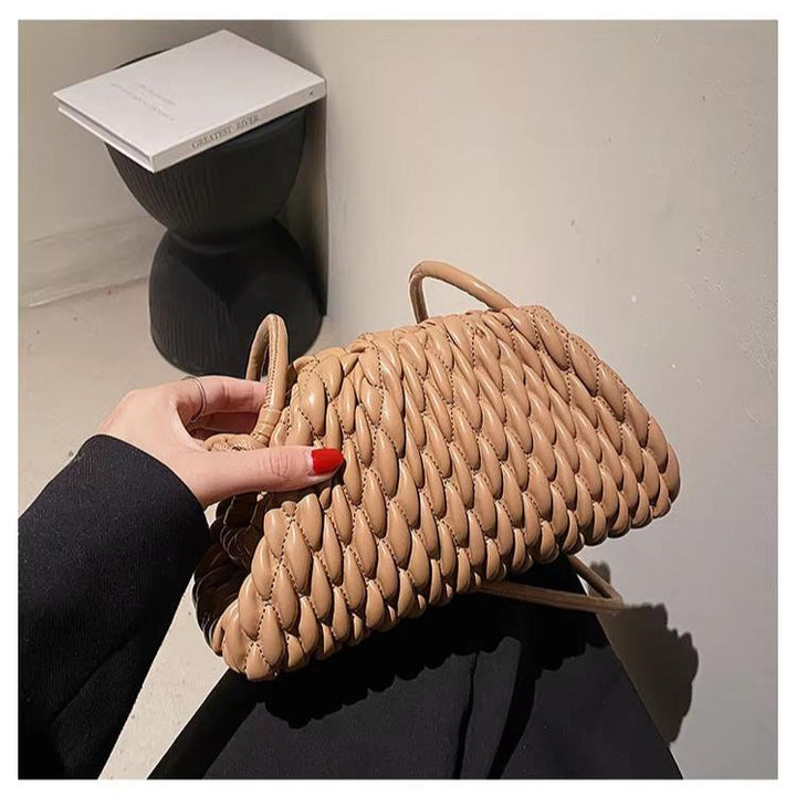 Borsa intrecciata beige in pelle, design moderno, manici corti, su sfondo minimalista. Accessorio moda donna elegante e chic.