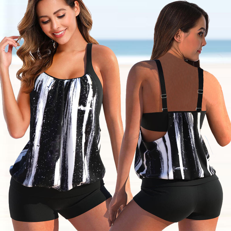 Donna in canotta sportiva nera e bianca, design a righe verticali, indossa shorts neri. Abbigliamento fitness estivo, spiaggia sullo sfondo.