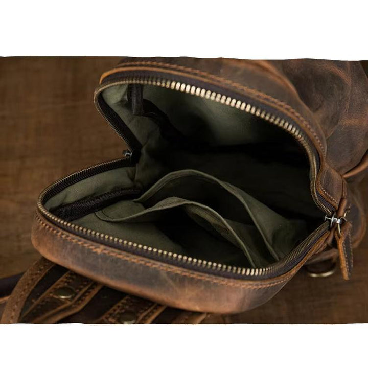 Zaino in pelle marrone vintage aperto, con scomparti interni visibili. Design robusto, ideale per viaggi e uso quotidiano. Accessorio moda uomo.