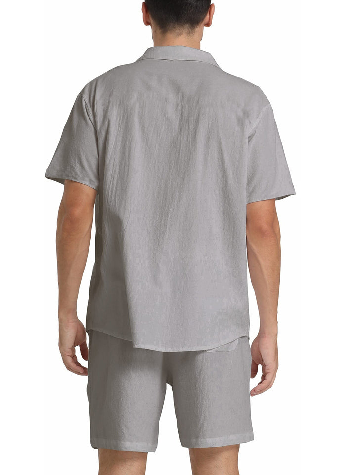 Uomo in completo estivo grigio chiaro, camicia a maniche corte e pantaloncini coordinati, moda casual, tessuto leggero, vista posteriore.