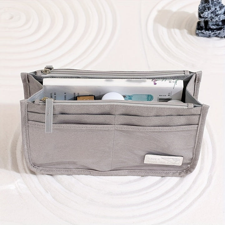 Organizer borsa grigio con tasche multiple, ideale per cosmetici e accessori. Design compatto, perfetto per viaggi e uso quotidiano.