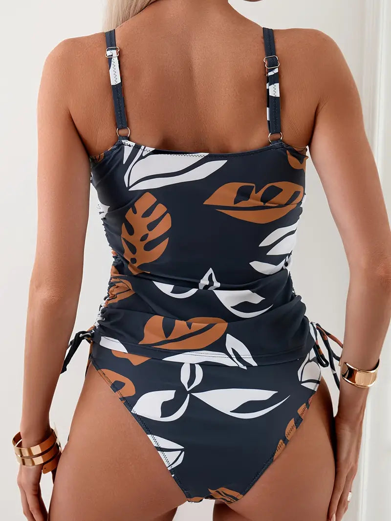 Costume intero donna con stampa foglie tropicali, spalline regolabili, colore blu scuro e marrone, moda mare estate 2023.