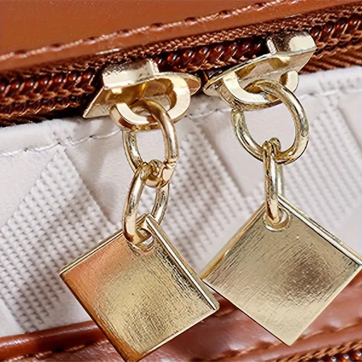 Cerniera in metallo dorato con pendenti quadrati su borsa in pelle marrone. Accessori moda eleganti, dettagli di lusso, chiusura resistente.