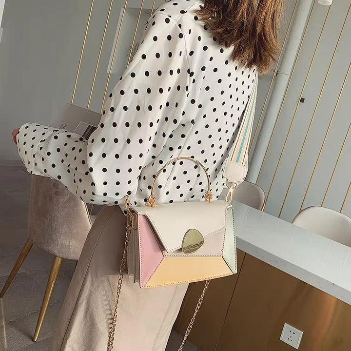 Donna con camicia a pois indossa borsa a tracolla multicolore geometrica, manico dorato, catena elegante. Accessorio moda femminile trendy.