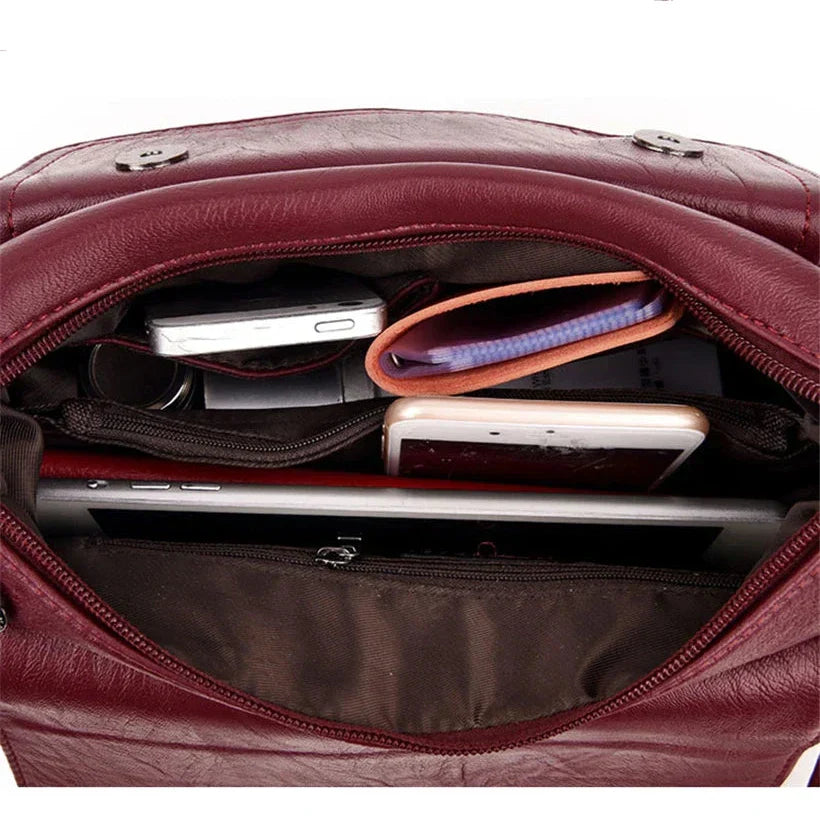 Interno di una borsa in pelle rossa con smartphone, portafoglio, tablet e occhiali. Accessori moda, organizzazione borsa, eleganza.