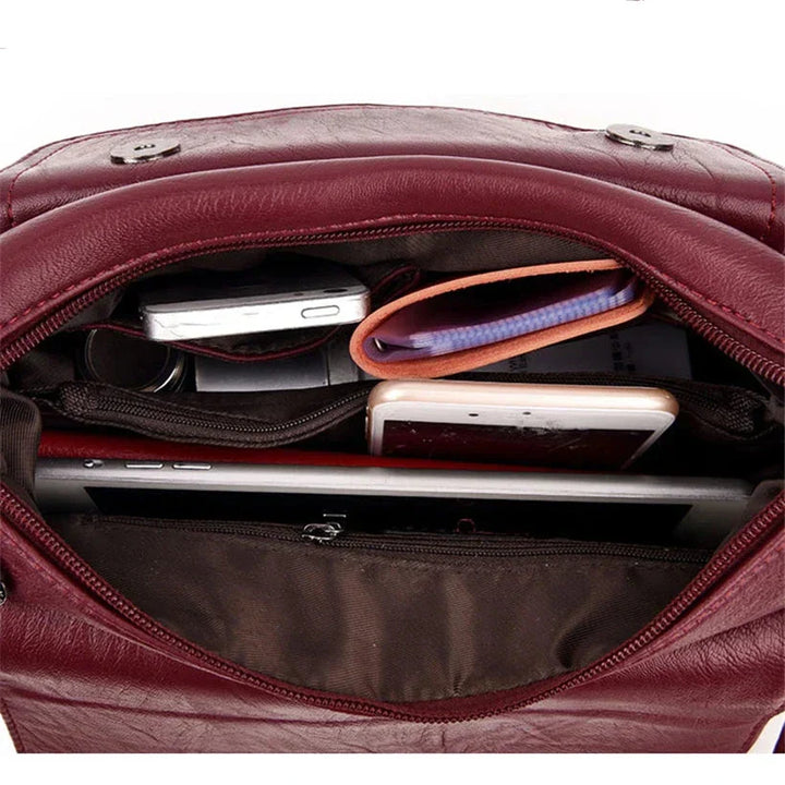 Interno di una borsa in pelle rossa con smartphone, portafoglio, tablet e occhiali. Accessori moda, organizzazione borsa, eleganza.