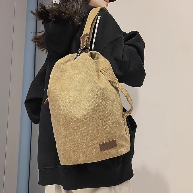 Zaino in tela beige su persona con cappotto nero, design minimalista, ideale per scuola o viaggio. Accessorio moda unisex, resistente e spazioso.