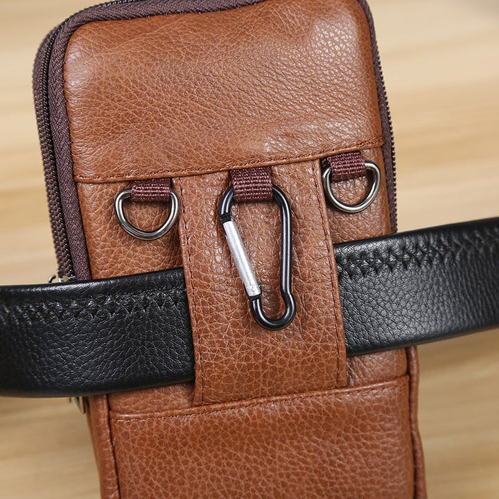 Marsupio in pelle marrone con moschettone e cintura nera, design elegante e pratico, ideale per viaggi e uso quotidiano. Accessorio moda uomo.