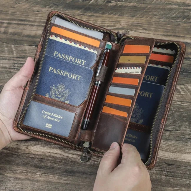 Portafoglio in pelle marrone con passaporto USA, scomparti per carte di credito e penna, su tavolo in legno. Accessorio viaggio elegante e funzionale.