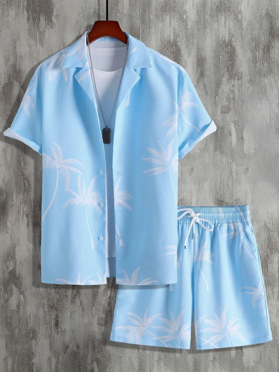 Completo estivo uomo azzurro con palme, camicia a maniche corte e pantaloncini coordinati. Moda casual, ideale per vacanze e look estivi.
