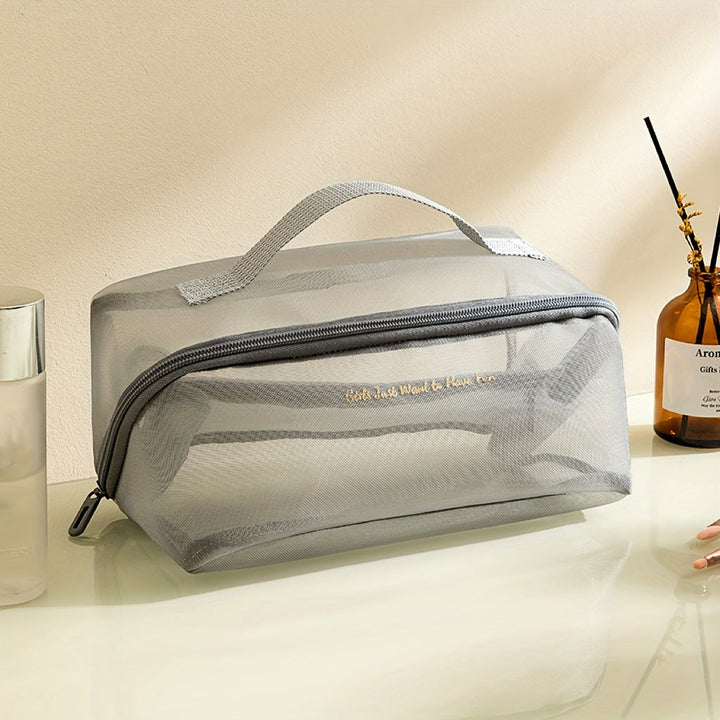 Borsa trasparente da viaggio in PVC grigio con cerniera, manico superiore, ideale per cosmetici e articoli da toeletta. Design elegante e funzionale.