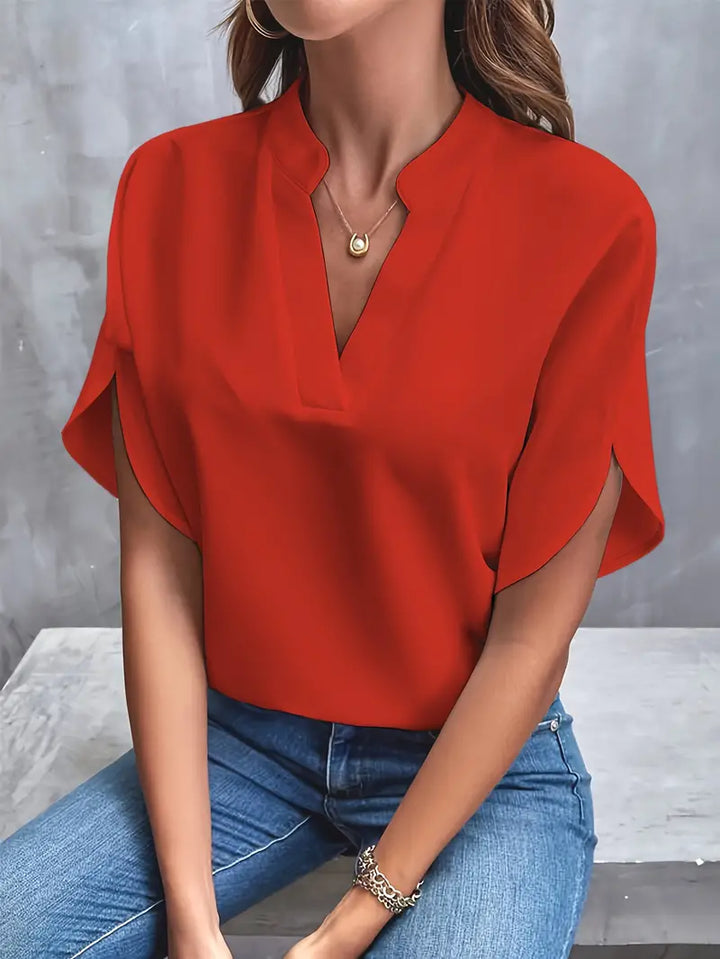 Blusa rossa elegante da donna con scollo a V, maniche corte, abbinata a jeans. Moda femminile casual, abbigliamento estivo, tendenze 2023.