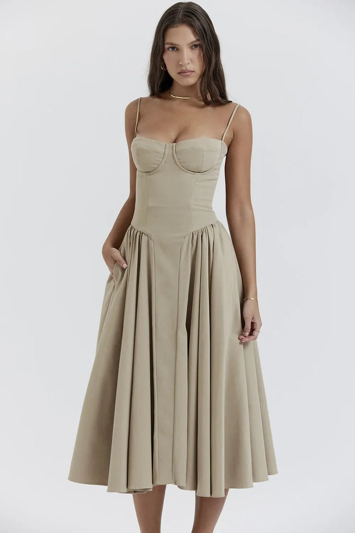 Abito midi beige elegante con spalline sottili e gonna ampia, indossato da modella. Perfetto per eventi formali e cerimonie.