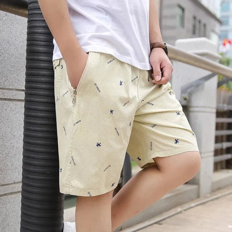 Pantaloncini beige da uomo con stampa, tasche laterali e zip, indossati con maglietta bianca. Ideali per moda estiva casual e comfort quotidiano.