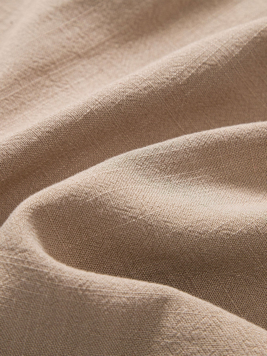 Tessuto di lino beige, trama naturale, texture morbida e ondulata, ideale per abbigliamento e arredamento. Materiale ecologico e traspirante.