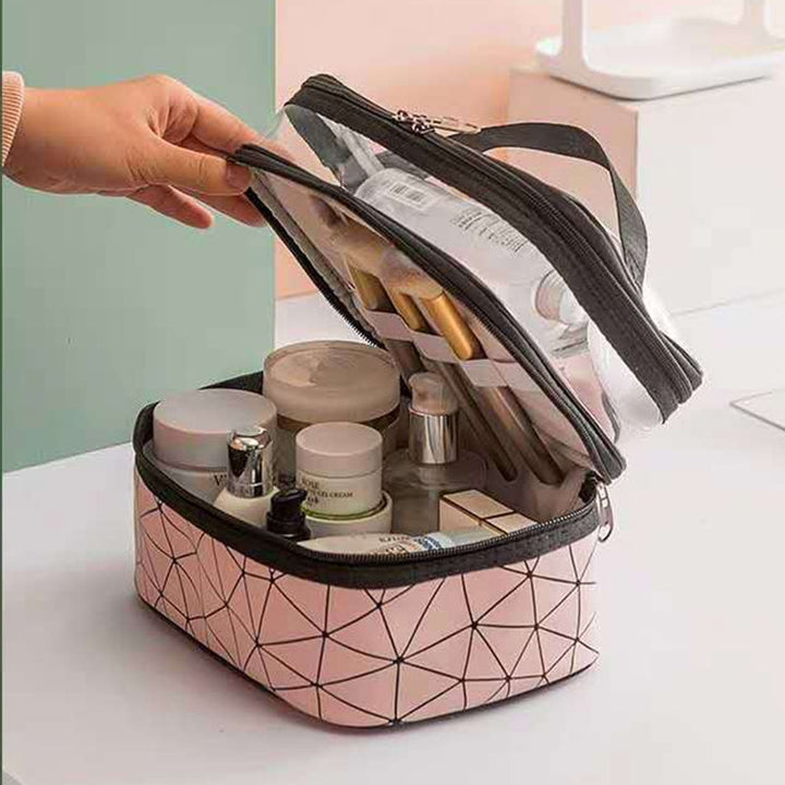 Borsa cosmetica rosa con motivo geometrico, doppio scomparto trasparente, contenente pennelli trucco, creme e flaconi. Ideale per organizzare cosmetici.