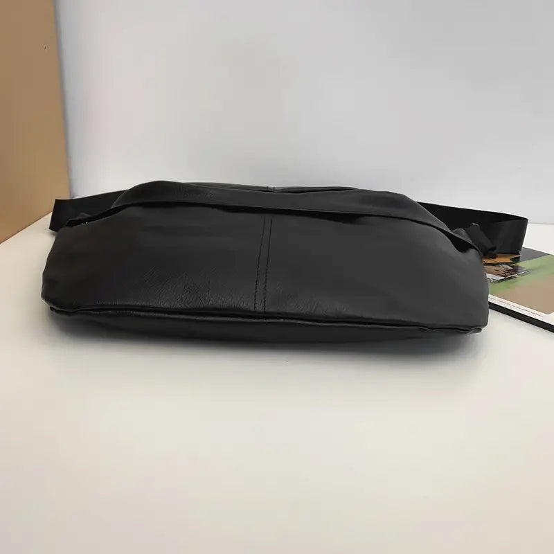 Borsa a tracolla in pelle nera su sfondo bianco, design elegante e moderno, ideale per uomo e donna, accessorio moda versatile e pratico.