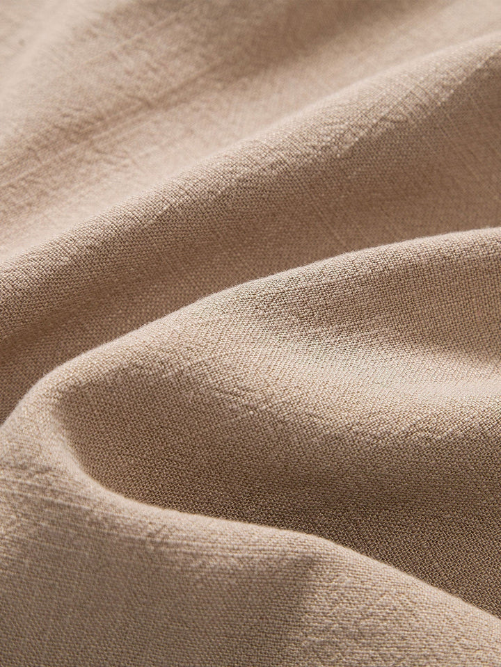 Tessuto di lino beige, trama naturale, texture morbida e ondulata, ideale per abbigliamento e arredamento, alta qualità e resistenza.